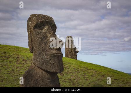 Due statue Moai sorgono su una collina erbosa dell'Isola di Pasqua Foto Stock