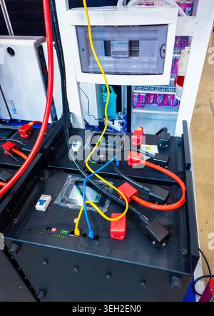 Una visione ad angolo alto di una configurazione professionale di stoccaggio delle batterie con unità di grande capacità, cablaggio colorato e pannelli di controllo digitali per applicazioni rinnovabili Foto Stock