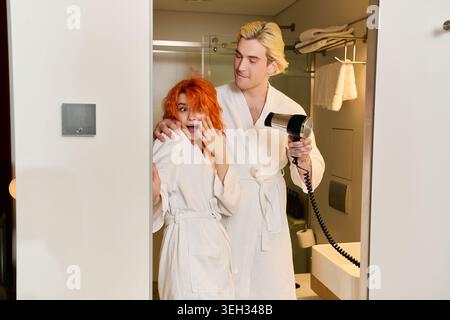 La coppia condivide risate e gioia mentre si prepara nella loro elegante camera d'albergo. Foto Stock