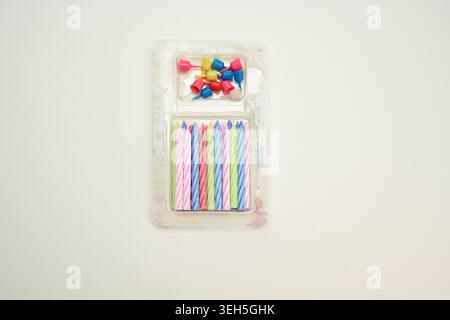 Candele colorate a strisce per compleanno con piccoli supporti disposti su uno sfondo pulito, una decorazione festiva per feste e torte Foto Stock