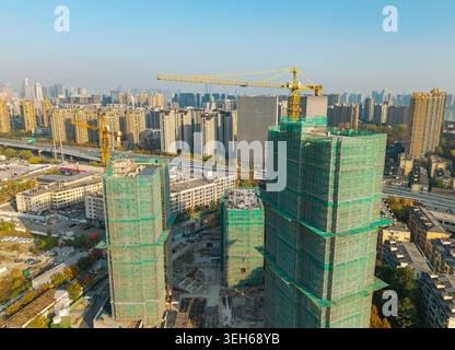 Moderno sviluppo urbano che mostra numerosi edifici alti in costruzione con reti verdi e prominenti gru a torre Foto Stock