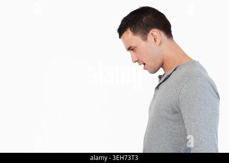 Uomo che posa il profilo destro in henley grigio, testa inclinata, parla verso lo sfondo bianco, copia spazio Foto Stock