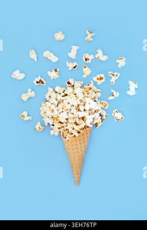 Surreale gelato estivo a base di popcorn con cornetta su sfondo blu e mais sciolto. Divertimento vacanze estive cibo arte design stravagante. Foto Stock