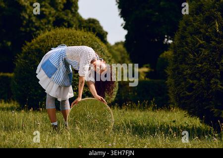 Una bella giovane donna balla liberamente tra il verde lussureggiante, incarnando uno spirito magico. Foto Stock