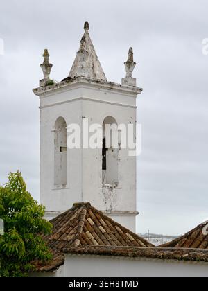 Tavira, Algarve, torre campanaria della chiesa portoghese sopra i tradizionali tetti piastrellati nella storica città vecchia. Foto Stock