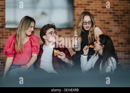 Gli adolescenti si ritrovano a mangiare pizza e a socializzare all'interno con bevande e risate Foto Stock