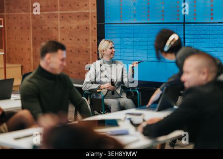 Incontro di lavoro con una donna leader su una sedia a rotelle che presenta i dati ai colleghi in un ufficio moderno Foto Stock