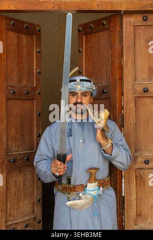 Un interprete di al-Razha (danza guerriera energica e ritmica) in tradizionale abbigliamento Oman con spada e scudo presso la Fortezza Nizwa a Nizwa, Oman Foto Stock