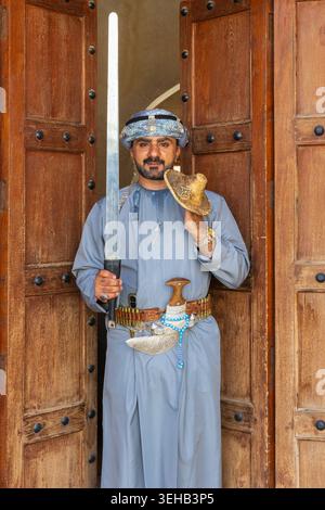 Un interprete di al-Razha (danza guerriera energica e ritmica) in tradizionale abbigliamento Oman con spada e scudo presso la Fortezza Nizwa a Nizwa, Oman Foto Stock