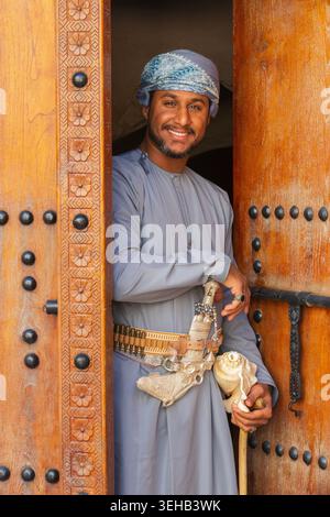 Un interprete di al-Razha (danza guerriera energica e ritmica) in abiti tradizionali dell'Oman con conchiglia e pugnale nella Fortezza di Nizwa a Nizwa, Oman Foto Stock