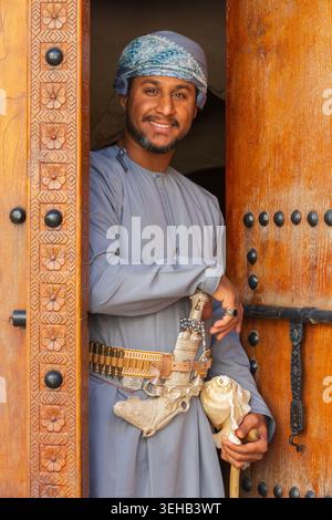 Un interprete di al-Razha (danza guerriera energica e ritmica) in abiti tradizionali dell'Oman con conchiglia e pugnale nella Fortezza di Nizwa a Nizwa, Oman Foto Stock