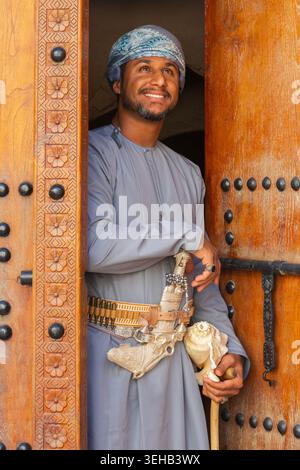 Un interprete di al-Razha (danza guerriera energica e ritmica) in abiti tradizionali dell'Oman con conchiglia e pugnale nella Fortezza di Nizwa a Nizwa, Oman Foto Stock