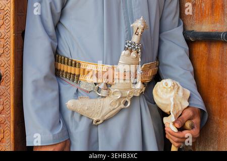 Primo piano dello strumento della conchiglia (conchiglia) e del pugnale (khanjar) di un artista omanita al-Razha nella fortezza di Nizwa a Nizwa, Oman Foto Stock