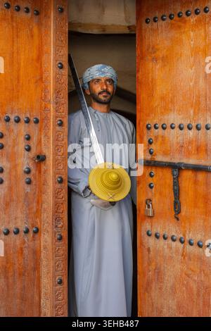 Un interprete di al-Razha (danza guerriera energica e ritmica) in tradizionale abbigliamento Oman con spada e scudo presso la Fortezza Nizwa a Nizwa, Oman Foto Stock