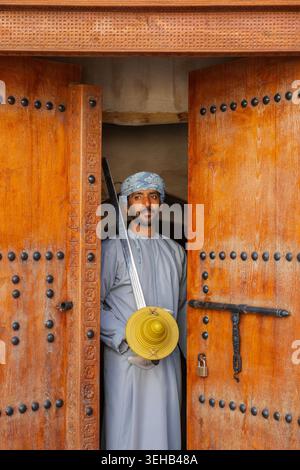 Un interprete di al-Razha (danza guerriera energica e ritmica) in tradizionale abbigliamento Oman con spada e scudo presso la Fortezza Nizwa a Nizwa, Oman Foto Stock