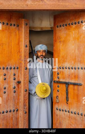 Un interprete di al-Razha (danza guerriera energica e ritmica) in tradizionale abbigliamento Oman con spada e scudo presso la Fortezza Nizwa a Nizwa, Oman Foto Stock
