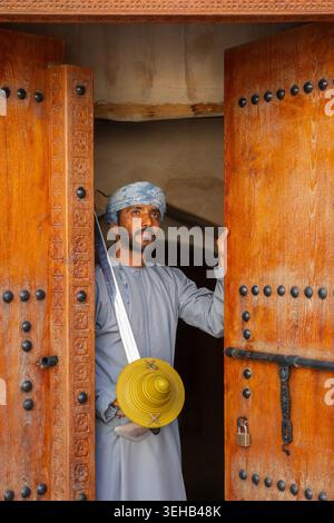 Un interprete di al-Razha (danza guerriera energica e ritmica) in tradizionale abbigliamento Oman con spada e scudo presso la Fortezza Nizwa a Nizwa, Oman Foto Stock
