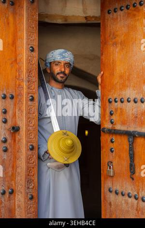 Un interprete di al-Razha (danza guerriera energica e ritmica) in tradizionale abbigliamento Oman con spada e scudo presso la Fortezza Nizwa a Nizwa, Oman Foto Stock
