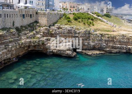 Polignano a Mare, Italia, Puglia - 24 maggio 2024: Spiaggia di Lama Monachile, situata tra le pittoresche scogliere sul mare Adriatico. Persone che nuotano in acqua Foto Stock