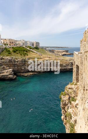 Polignano a Mare, Italia, Puglia - 24 maggio 2024: Spiaggia di Lama Monachile, situata tra le pittoresche scogliere sul mare Adriatico. Persone che nuotano in acqua Foto Stock