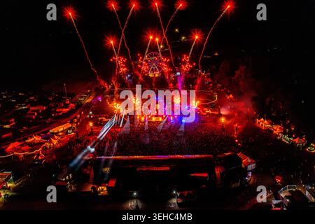 Herzogenaurach, Germania - 27 luglio 2025: Veduta aerea dell'Open Beatz Festival con fuochi d'artificio rossi, una grande folla e una ruota panoramica di notte. Foto Stock