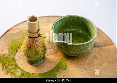 Latte matcha freddo in tazza su vassoio di legno con luce solare estiva. Superficie in schiuma cremosa e rinfrescante colore verde nella presentazione in stile caffetteria. Somma Foto Stock