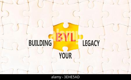 BYL sta costruendo il tuo simbolo legacy. Parole concettuali BYL costruisce la tua eredità su splendidi rompicapo bianchi. Bellissimo sfondo giallo. Business BYL Building Foto Stock