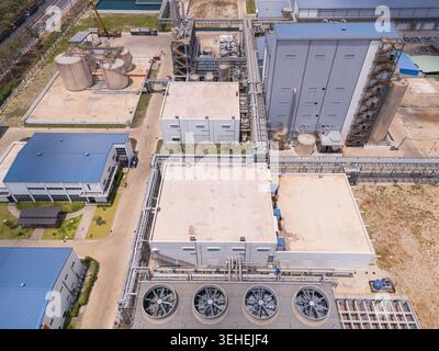 Vista aerea dall'alto di un moderno complesso industriale con serbatoi di stoccaggio, tubazioni e grandi ventilatori di torri di raffreddamento Foto Stock