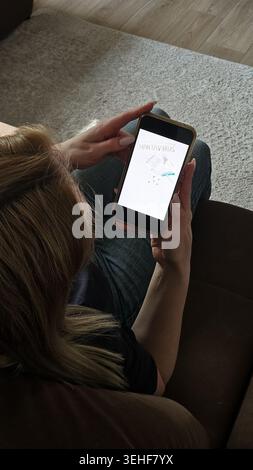 Immagine di stile di vita in primo piano di smartphone che mostra il testo di avvertimento hantavirus nelle mani della donna a casa. Moderno concetto sanitario ed epidemico. Alle 9:16 Foto Stock