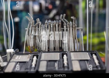 Display per strumenti di estrazione dentaria in acciaio inox. Primo piano di strumenti di estrazione dentale in acciaio inox lucido disposti su un rack con sistema chirurgico Foto Stock
