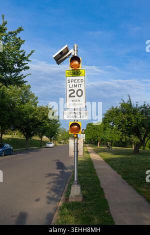 Un cartello con limite di velocità scolastico di 20 posti con pannello solare e luci di emergenza si trova accanto a una strada asfaltata e marciapiede vicino a Baker Park a Frederick, Mary Foto Stock
