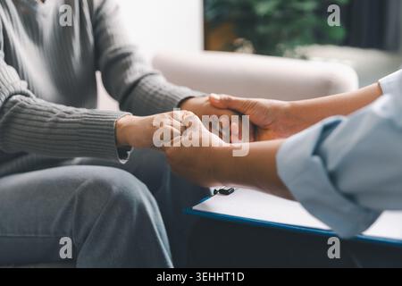 Primo piano del terapeuta che tiene le mani del paziente durante la sessione di consulenza sulla salute mentale, esprimendo empatia, fiducia, rassicurazione, supporto emotivo, healin Foto Stock
