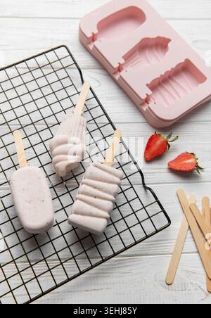 Tre fragole essiccate su una griglia con una muffa rosa e fragole fresche Foto Stock