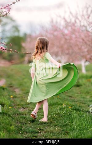 Ragazza che tiene in mano un vestito in un frutteto in fiore rosa Foto Stock