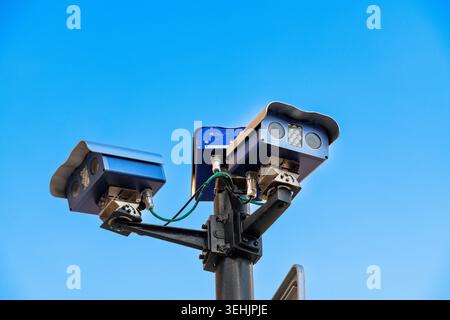 Palma - Isole Baleari - Spagna - 01-01-2026: Due telecamere di sorveglianza blu con cavi montati su un alto palo metallico, fotografate dal basso contro un cielo azzurro chiaro alla luce del giorno. Foto Stock
