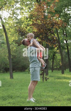 Gioioso momento di famiglia. Energici legami familiari catturati durante la giornata di sole nel lussureggiante parco Foto Stock