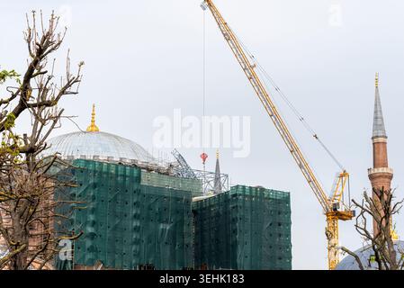 I lavoratori sono impegnati nella costruzione di una grande struttura in città. Una gru solleva i materiali mentre l'impalcatura sostiene la cupola e i lati. Nelle vicinanze, a un chilometro e mezzo circa Foto Stock