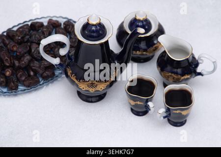 Set da caffè con decanter, crema, ciotola per zucchero blu e due tazze . Stoviglie vintage. Frutta dolce di datteri. Foto Stock