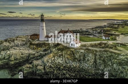 Veduta aerea di Portland Head Light su scogliere rocciose con edifici bianchi sotto un cielo al tramonto Cape Elizabeth, Maine, Stati Uniti. Foto Stock
