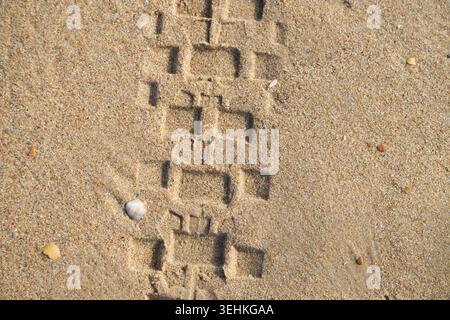 Impronta di pneumatici per auto su spiaggia sabbiosa Foto Stock