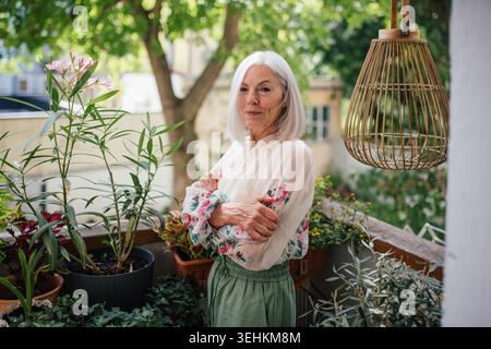 Ritratto di una bella donna anziana in piedi sul balcone. Foto Stock