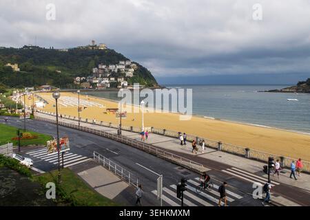 Vista panoramica della baia di la Concha con la spiaggia, l'isola di Santa Clara e il Monte Igueldo sotto un cielo nuvoloso a San Sebastian, Spagna, Europa Foto Stock