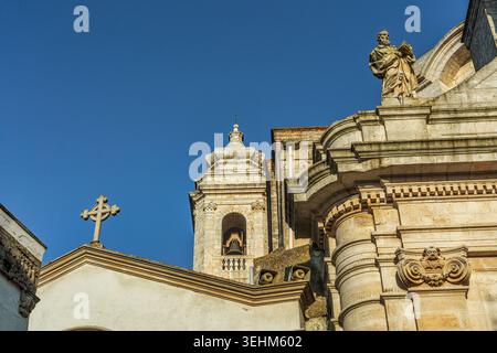 Una vista della chiesa barocca di San Giorgio Martire, con il suo suggestivo campanile, la croce prominente e la statua di un venerato santo. Locorotondo, Puglia Foto Stock