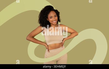 La donna indossa con sicurezza abiti Activewear beige su sfondo verde Foto Stock