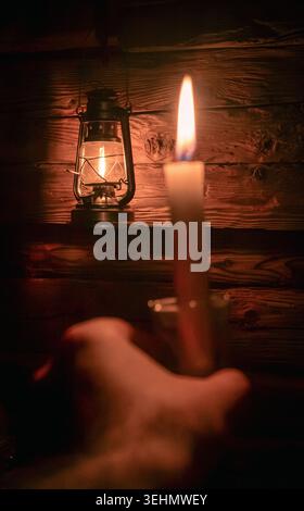 Una candela singola illuminata e una lanterna classica proiettano un caldo bagliore in una stanza poco illuminata, creando un'atmosfera rilassante e serena, simboleggiando il fascino del vecchio mondo Foto Stock