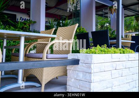 Tavoli in legno e sedie in rattan intrecciato in una zona di svago contemporanea. Foto Stock