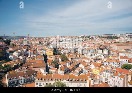 Ampia vista panoramica su Lisbona, Portogallo, con tetti di tegole rosse, architettura storica e facciate luminose sotto un cielo limpido, con il Tago R. Foto Stock