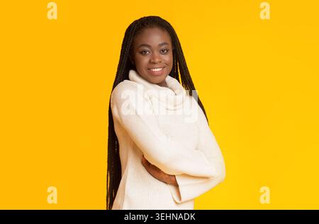Sfondo giallo brillante con una donna sorridente in un comodo pullover Foto Stock