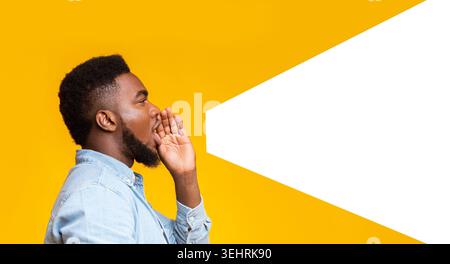 Guy rendendo forte annuncio a copia spazio su sfondo giallo Foto Stock