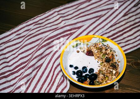 Sana ciotola per frullato di mirtilli con granola e frutti di bosco freschi su un tavolo rustico in legno Foto Stock
